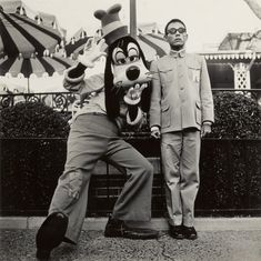 an old black and white photo of two men dressed as goofy the dog in front of a carnival