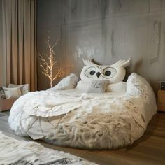 an owl shaped bed with white fur on the bottom and pillows in front of it