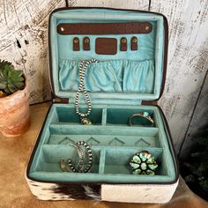 The Addie Flatts Jewelry Tote~ We Love All things Unique! What a Great Way to Store your Jewelry Collection!! Perfect for Travel too!! Cowhide front and sides with Tooled Leather center for that something Extra!! Turquoise Velvet interior keeps and divided compartments for storage to keep organized! Why fit In! ~Cowhide front & sides ~Cowhide Dark Brown & White (colors/shape will vary slightly) ~Tooled Leather center with buckstitch trim ~Dark Brown Marbled Leather bottom ~Double Zippered Closur Cowhide Jewelry Case, Conch Stud, Cactus Necklace, Horseshoe Pendant, Velvet Interior, Velvet Interiors, White Colors, Tooled Leather, Color Shapes