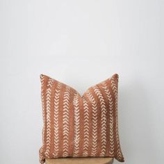 an orange and white pillow sitting on top of a wooden shelf next to a wall