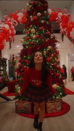 a woman standing in front of a christmas tree