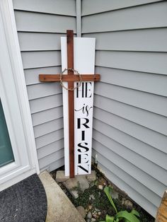 a wooden cross on the side of a house next to a flower pot and door