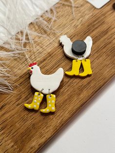 two wooden roosters with yellow boots and polka dots on them sitting on a wood board