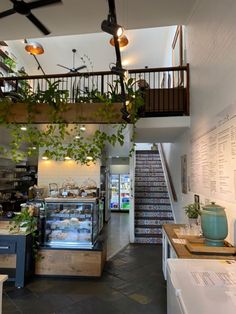 the inside of a restaurant with plants hanging from the ceiling and stairs leading up to the second floor