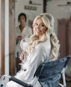 a woman sitting in a chair holding a mirror