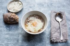 an egg is in a bowl next to two spoons and a napkin on a table