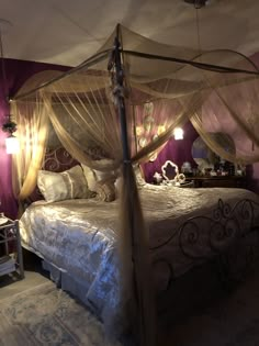 a canopy bed in a bedroom with purple walls