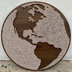 a wooden sign with the earth drawn on it's side, in front of a white wall