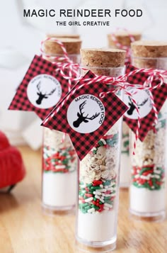 three glass bottles filled with christmas treats on top of a wooden table next to a candy bar