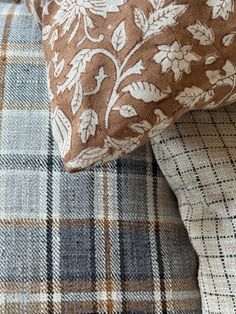 two pillows sitting next to each other on top of a plaid pillow case with floral designs