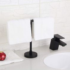 two white towels are hanging on a black stand in front of a sink and mirror