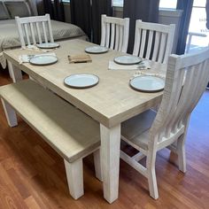 a wooden table with white chairs and plates on it