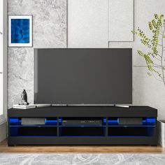 an entertainment center with blue lights on the sides and a large screen tv mounted to it's side