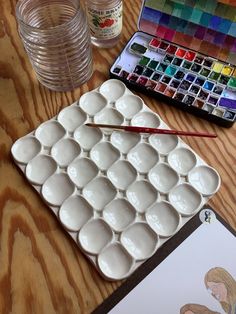 a table with paint and water bottles on it, including an artist's palette