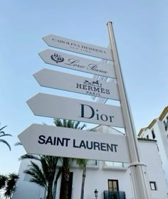 there are many signs on the pole in front of this building that says dior saint laurent