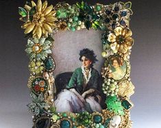 an old fashion picture frame with flowers and pearls on it's sides, featuring a woman sitting in a chair