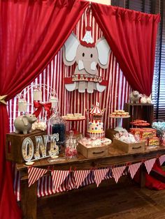 an elephant themed birthday party with red drapes and candy bars on the side table