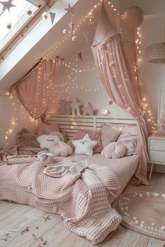 a bedroom decorated in pink and white with fairy lights on the ceiling, bedding and rugs