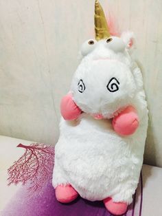 a stuffed unicorn with a gold horn on it's head sitting on a purple surface