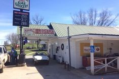 a gas station with cars parked in front of it and people standing outside the building