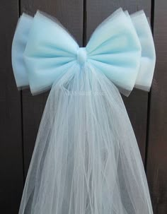 a white tulle bow tied to the back of a veil on a wooden door