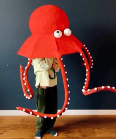 a young boy is holding an octopus shaped umbrella in front of his face and head