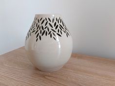 a white vase sitting on top of a wooden table