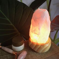 a himalayan salt lamp sitting on top of a wooden table next to a potted plant