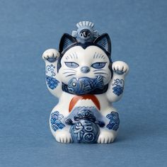 a ceramic cat figurine sitting on top of a blue surface with its paws up