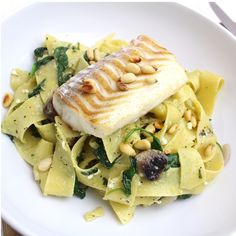 a white plate topped with pasta and fish