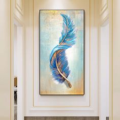 a blue feather painting hanging on the wall above a fireplace in a room with white walls