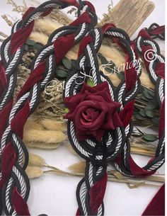 a red rose sitting on top of some black and white rope