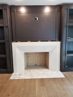 an empty living room with built in bookcases and a fire place on the far wall