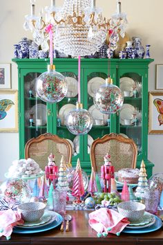 a dining room table set for christmas with plates, silverware and ornaments on it