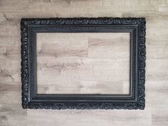 an old black frame hanging on the wall with wood planks in the background,