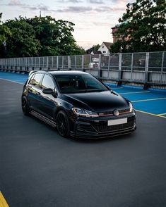 a black volkswagen golf gtr parked in a parking lot with blue and yellow lines