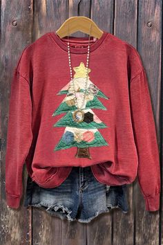 a women's sweatshirt with a christmas tree on the front, and a beaded necklace hanging from it