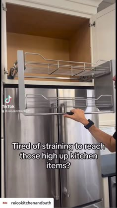 a man pointing to the bottom of a stainless steel refrigerator