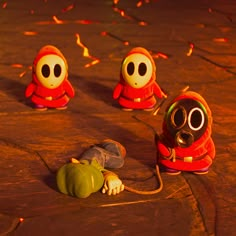 three small toy figures are sitting on the ground