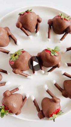 there are many chocolate candies shaped like horses on a white plate with strawberries