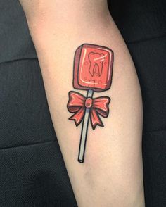 a red lollipop with a bow on it's thigh is featured in this tattoo