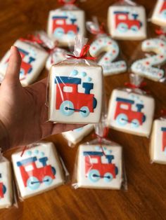 a hand is holding some decorated cookies in the shape of train tracks and cars on them