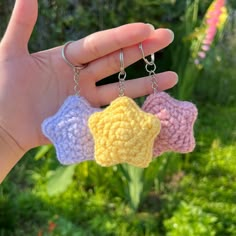 a hand holding three crocheted keychains in the shape of stars with chains