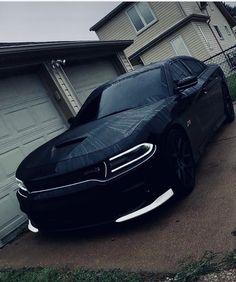 a black car parked in front of a house with a tarp on it's hood