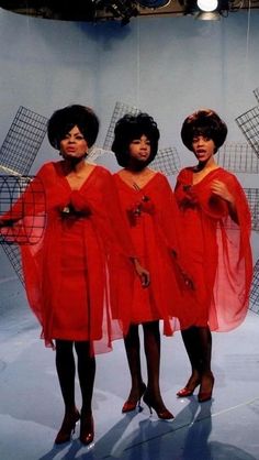 three women in red dresses standing next to each other with their hands on their hips