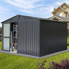 a large metal shed sitting on top of a lush green field next to a house