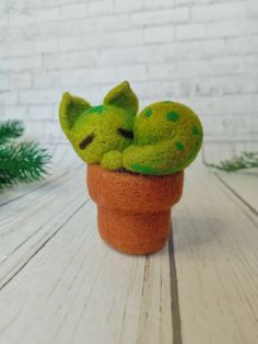 a small green cat sleeping in a potted plant