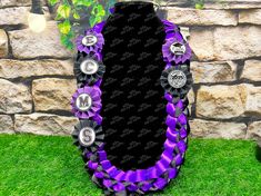 a purple and black ribbon with silver buttons on the front is in front of a stone wall