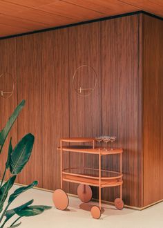 a room with wooden paneling and two glass vases on the floor next to a potted plant