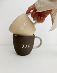 a person holding a spoon in a coffee cup with the word dad printed on it